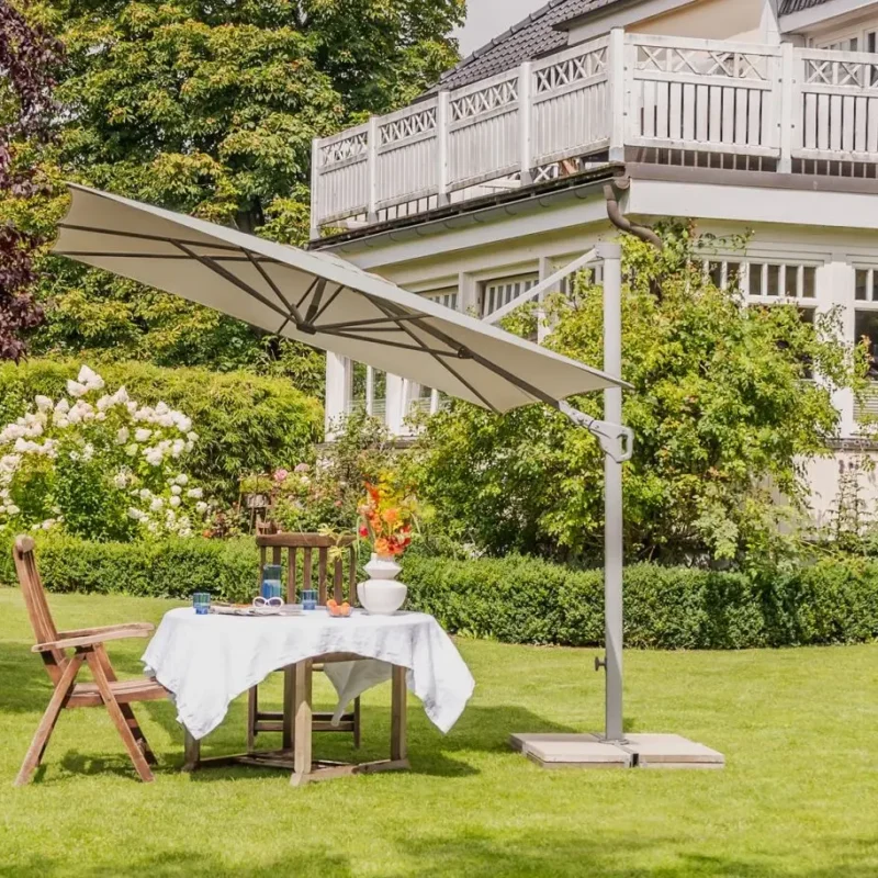 Parasol déporté inclinable Familyflex en situation sur une terrasse avec table de jardin.