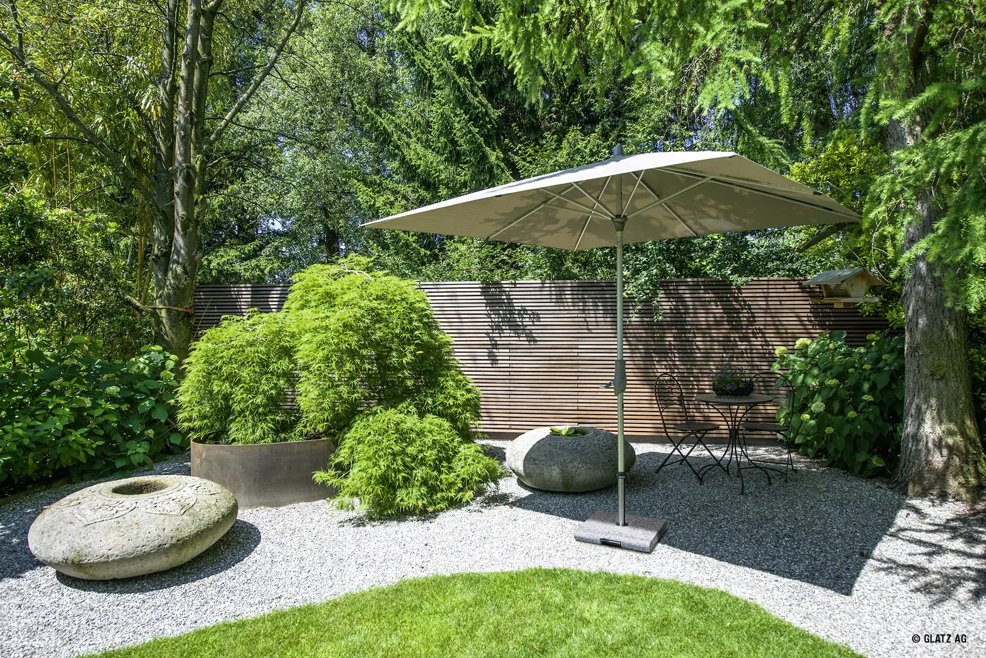 Parasol carré de terrasse Glatz ALU-TWIST gris sur un sol en gravier