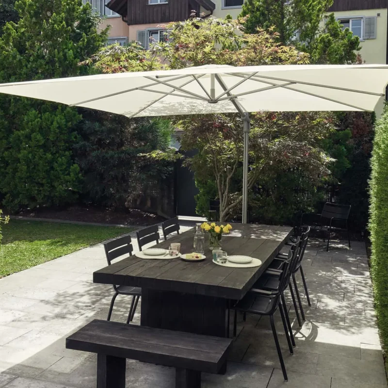 Grand parasol déporté aluminium Sunflex Suncomfort by Glatz installé sur une terrasse avec table en bois.