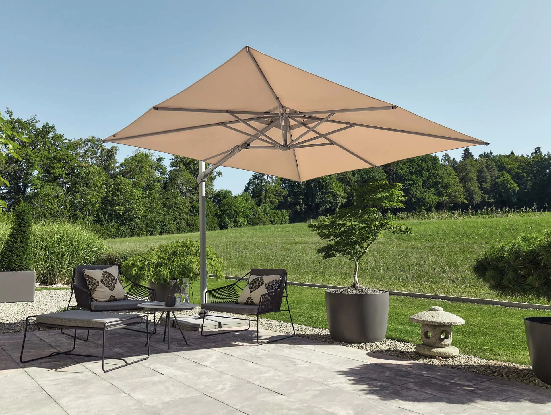 Mise en situation d'un parasol déporté inclinable latéralement Varioflex écru sur une terrasse en bois moderne.