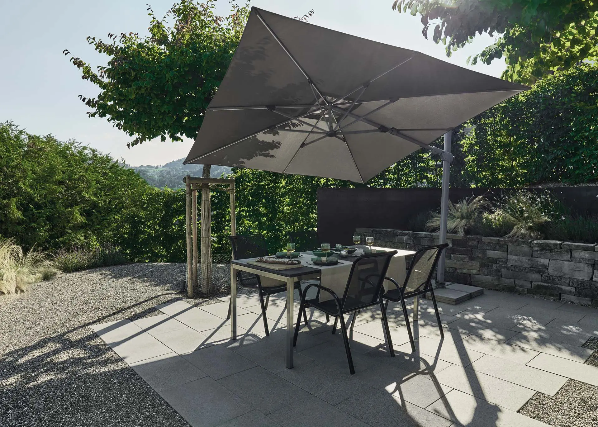 Salon de jardin moderne sous un parasol déporté LED solaire inclinable Suncomfort Light Grey.