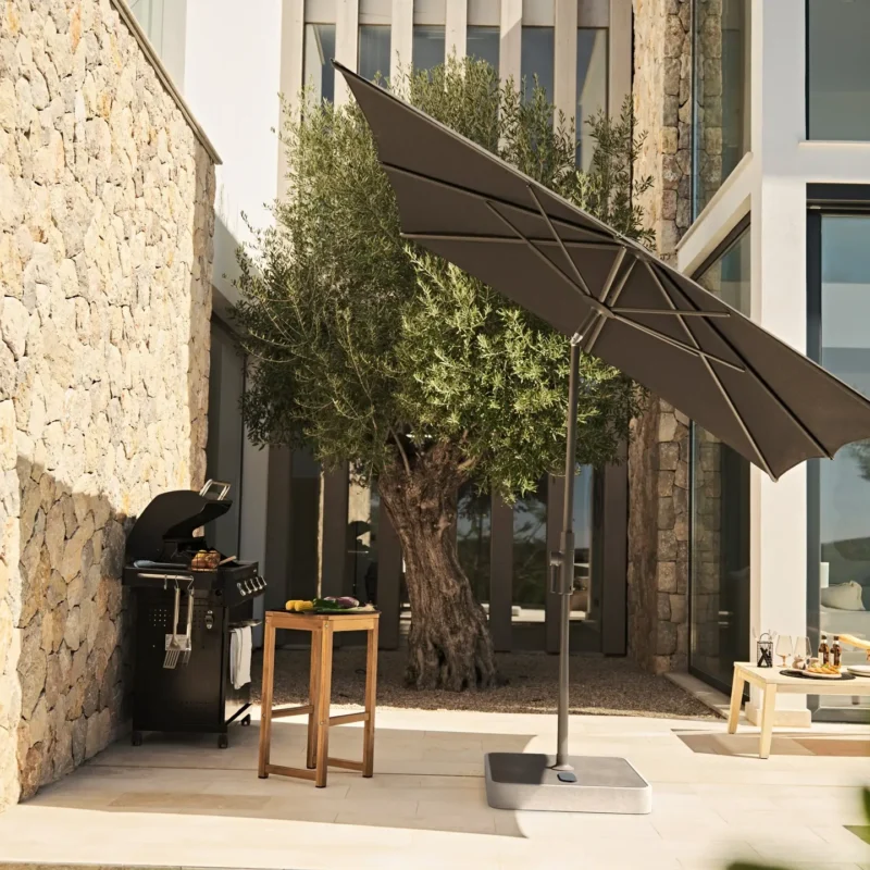 Parasol de terrasse inclinable Glatz ALU-TWIST noir à manivelle près d'un barbecue