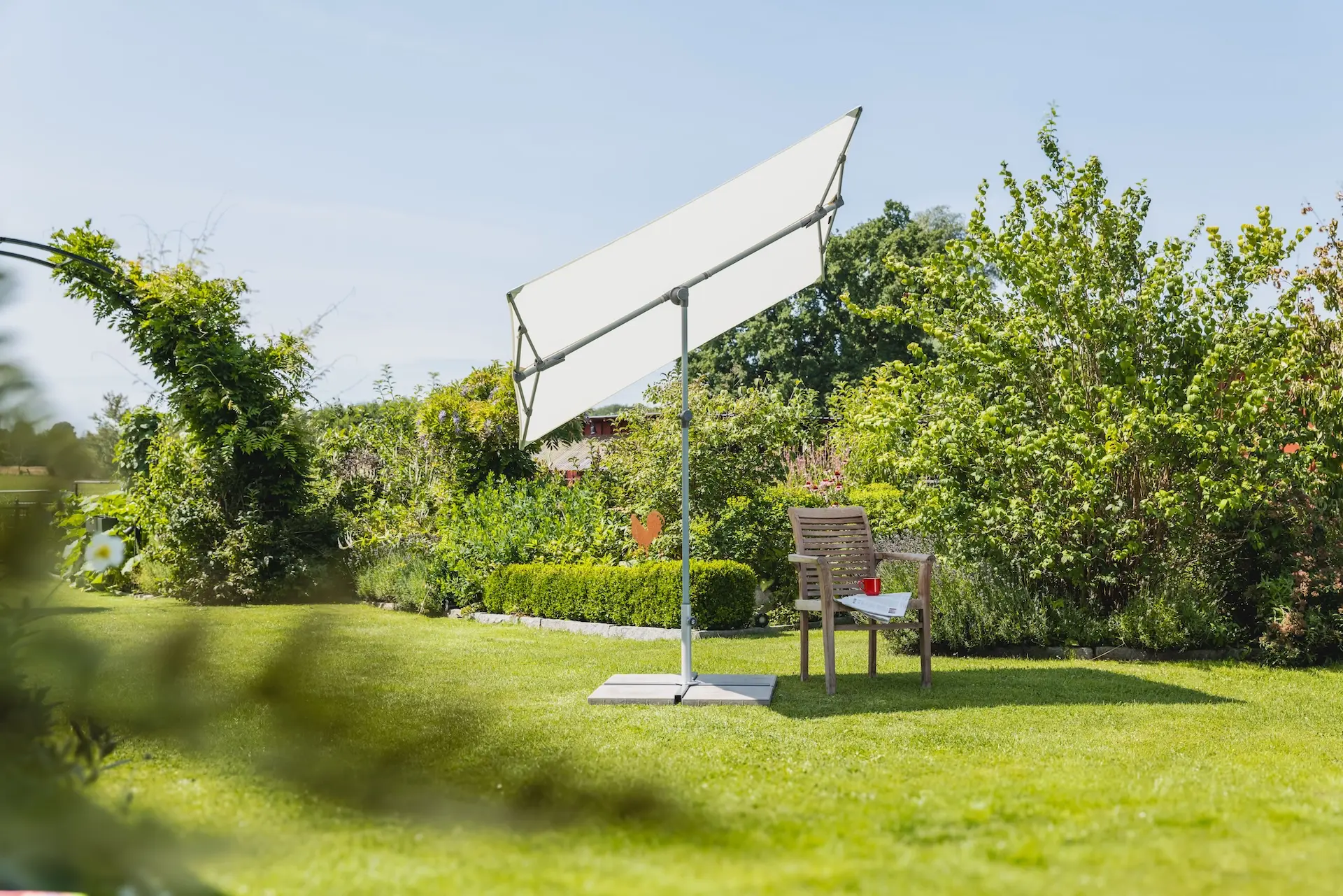 Parasol vertical de balcon Flex Roof Suncomfort coloris Sand White dans un jardin.