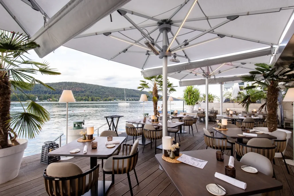 Aménagement de terrasse de restaurant gastronomique en front de mer avec parasols blancs.