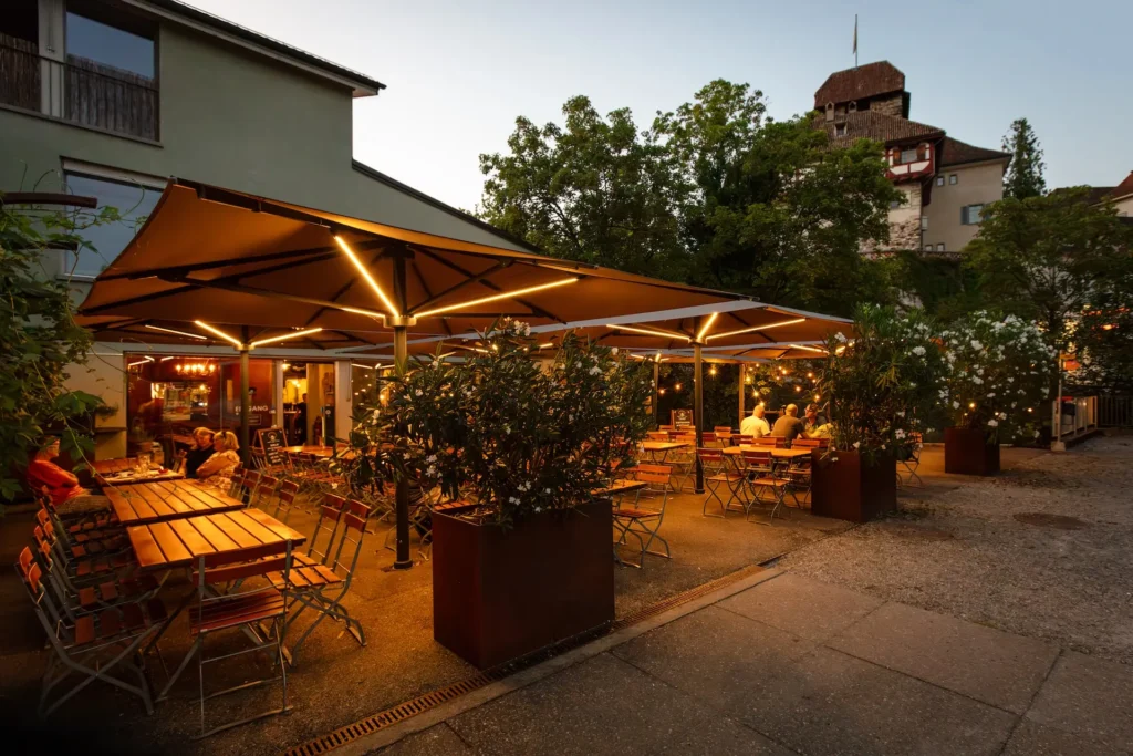Parasols Glatz avec éclairage LED intégré sur une terrasse de restaurant urbain.